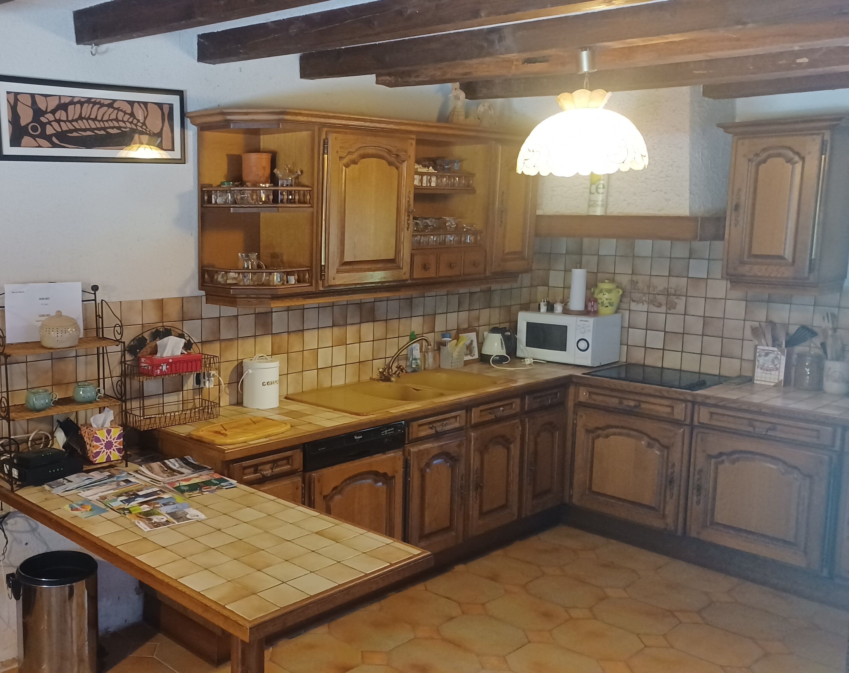 A kitchen with wooden cabinets, a tiled backsplash, a microwave, and a hanging light fixture.