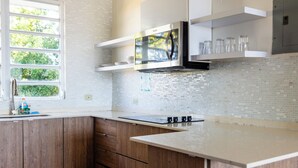 Una cocina moderna con armarios de madera, un microondas de acero inoxidable y un salpicadero de azulejos.