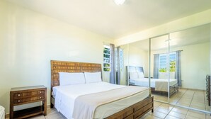 Un dormitorio con cama de madera, mesita de noche, espejo grande y puerta corrediza que da a un balcón.