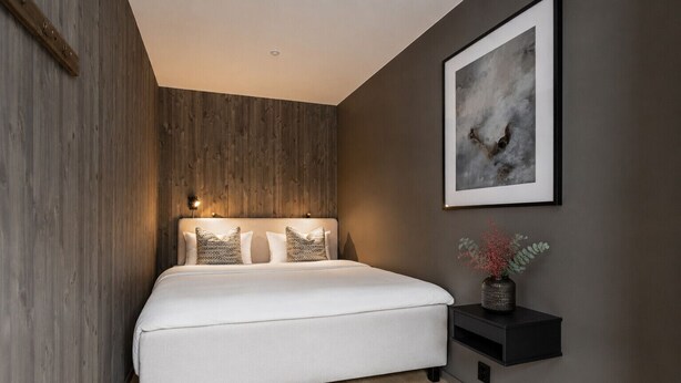 A modern bedroom with a bed, a nightstand, a wall-mounted shelf, and a framed abstract painting. - Ski-in / Ski-out apartment in Hemsedal (Hemsedal)