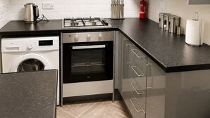 Eine moderne Küche mit Waschmaschine, Backofen und Gasherd.