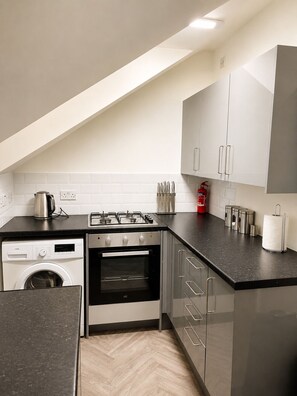 A modern kitchen with a washing machine, oven, and a gas stove. - Cozy 2 bedFlat with 50inch TVs (London)