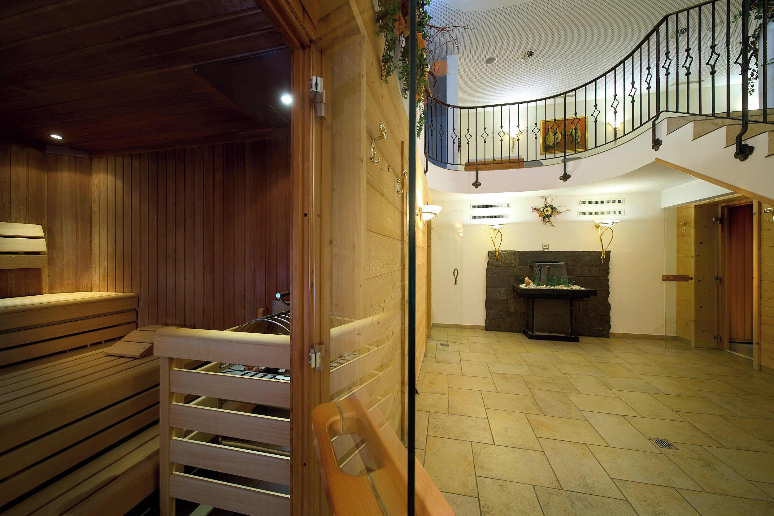 Interior de madera con un banco, una chimenea de piedra y una barandilla de metal.