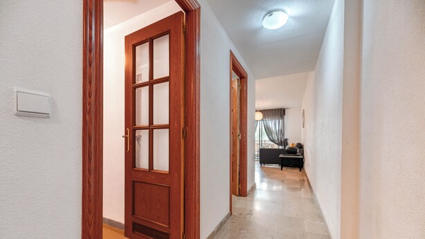 A hallway with wooden doors, a light switch, and a lamp. - LXR Marysol 2-Bedroom. Apt (Benalmádena)