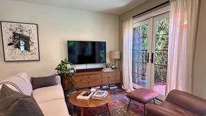 Uma sala de estar com um sofá, uma mesa de centro, uma televisão e um tapete estampado.
