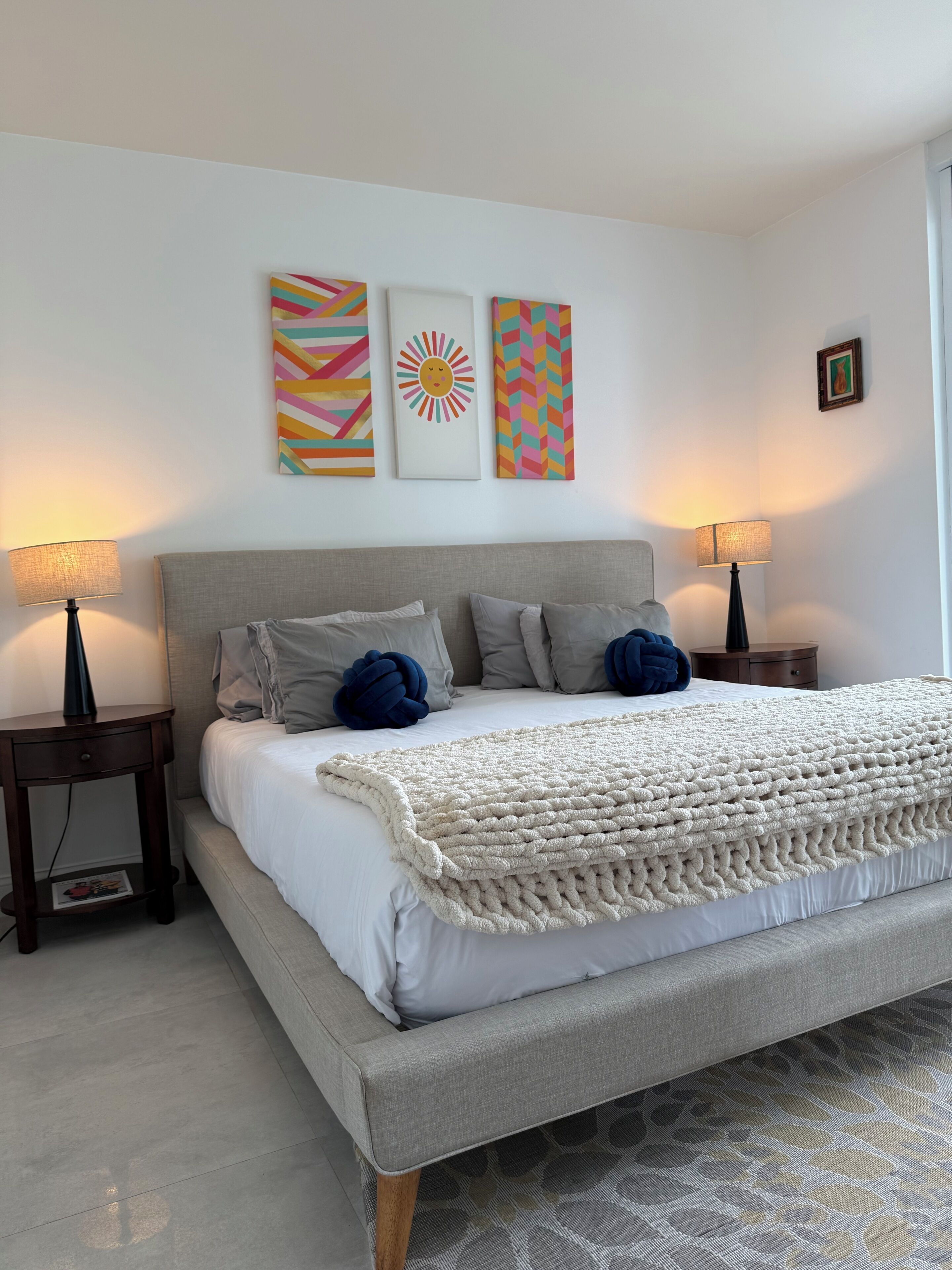 Een slaapkamer met een bed, twee nachtkastjes en drie wanddecoraties.