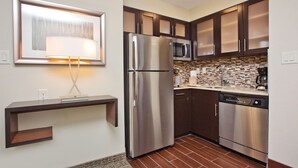 A modern kitchen with stainless steel appliances, dark wooden cabinets, and a tiled backsplash.