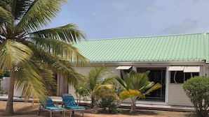 Una piscina con sillas de descanso, una palmera y un edificio con techo verde.