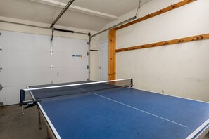 A ping pong table with a net in a room with white walls and a wooden beam. - Steps 2 Summit - Walk to Slopes, Pool Table (Big Bear Lake)