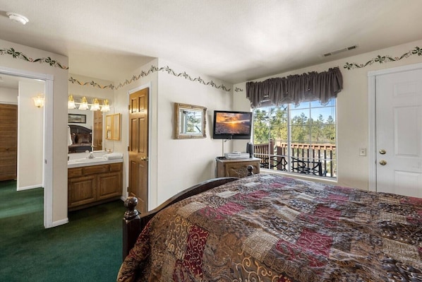 A bedroom with a large bed, a television, a balcony with a view, and a bathroom with a vanity. - Steps 2 Summit - Walk to Slopes, Pool Table (Big Bear Lake)