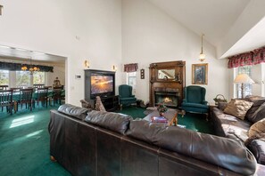 A spacious living room with a fireplace, leather sofas, a television, and a dining area with chairs and a table. - Steps 2 Summit - Walk to Slopes, Pool Table (Big Bear Lake)