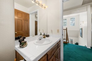 A bathroom with a double sink, a large mirror, and a wooden door. - Steps 2 Summit - Walk to Slopes, Pool Table (Big Bear Lake)