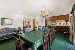 A dining area with a green table, wooden chairs, and a chandelier. - Steps 2 Summit - Walk to Slopes, Pool Table (Big Bear Lake)