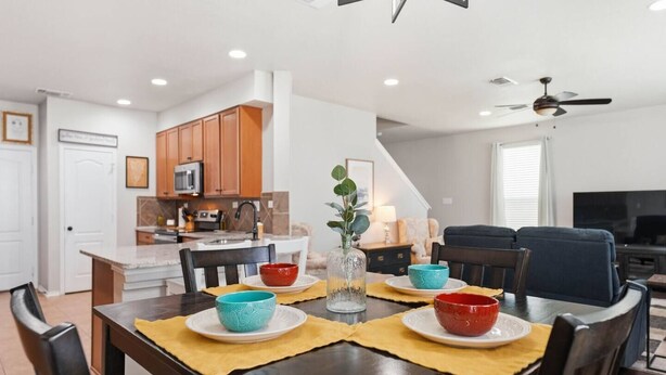 Una cocina moderna con armarios de madera, una mesa de comedor con sillas y una sala de estar con sofá y televisor.