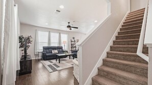 Una sala de estar con sofá, mesa de centro y una escalera.