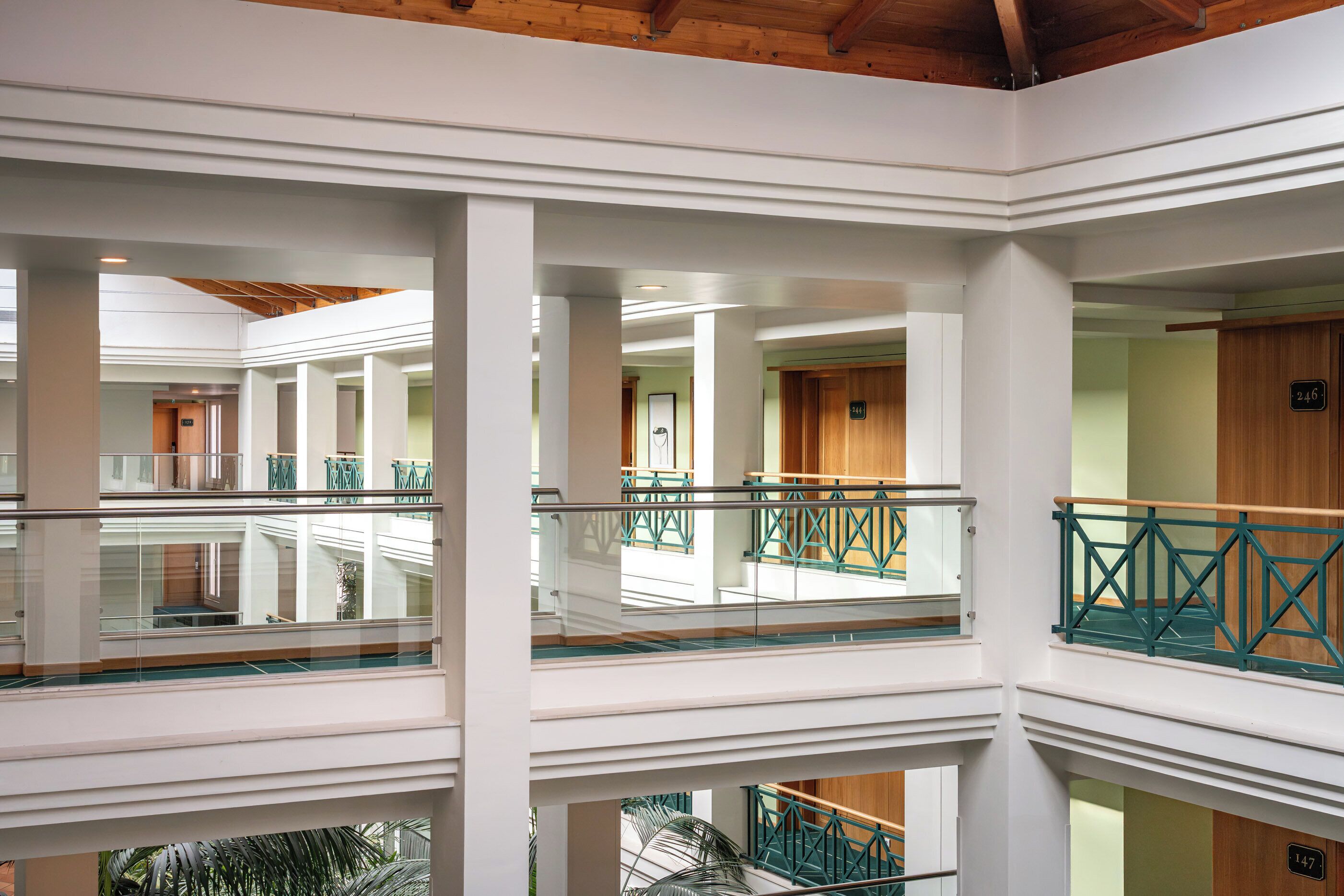 A multi-level interior with glass railings and wooden beams.