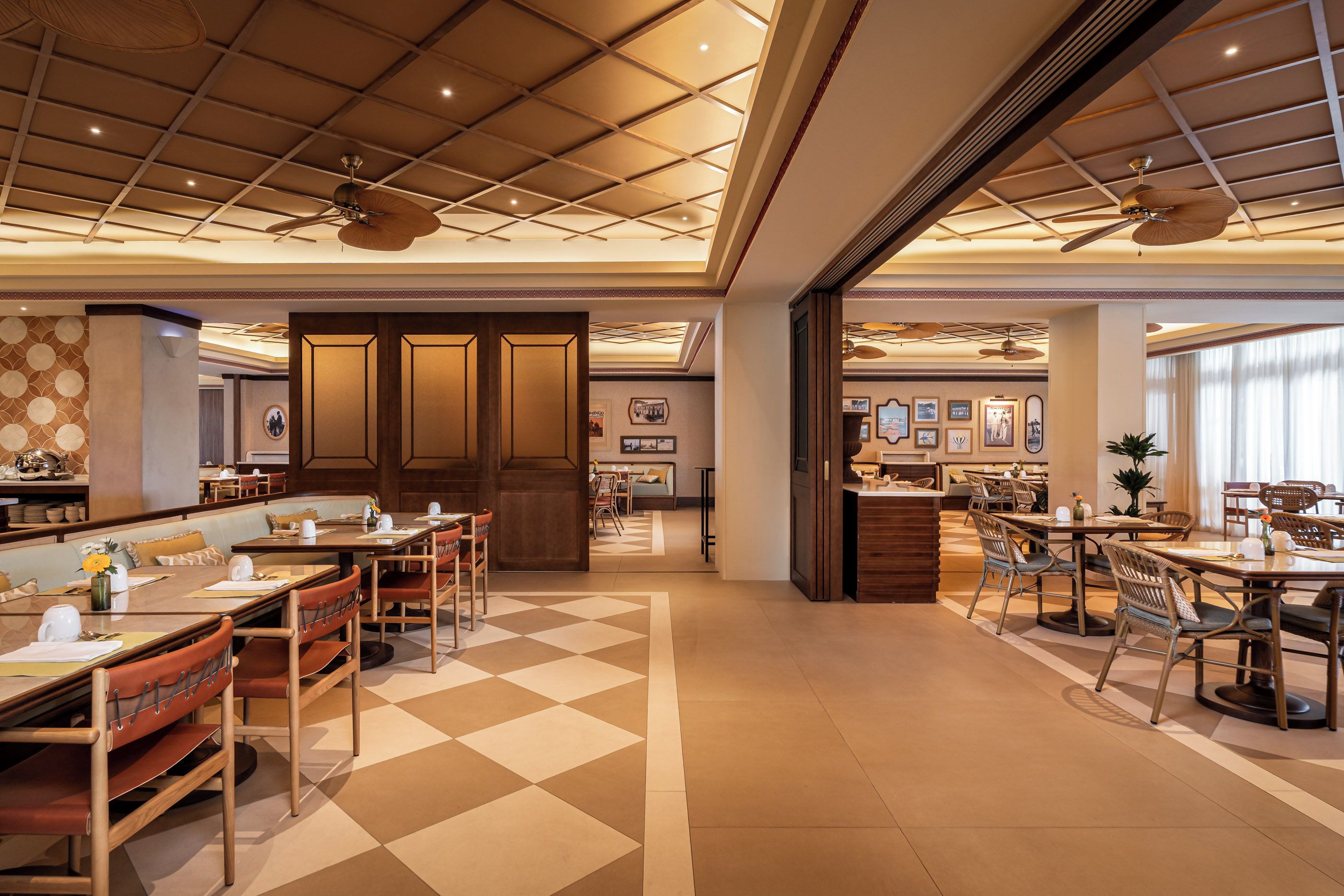 A spacious hotel lobby with a checkered floor, multiple dining areas, and ceiling fans.