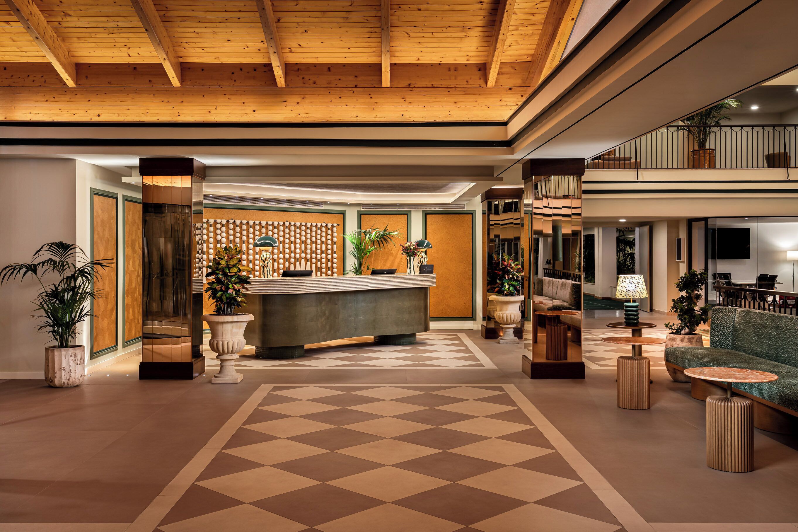 A lobby with a check-in counter, seating area, and a staircase leading to an upper level.