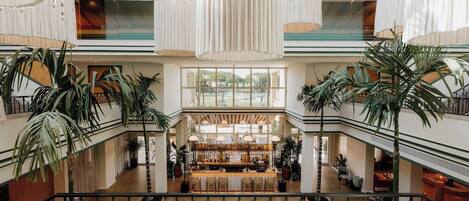 A spacious atrium with a central bar area, multiple levels with balconies, and large windows allowing natural light.