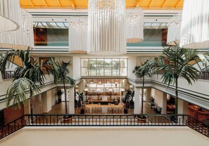 A spacious atrium with a central bar area, multiple levels with balconies, and large windows allowing natural light. - Kimpton Quinta da Marinha (Cascais)
