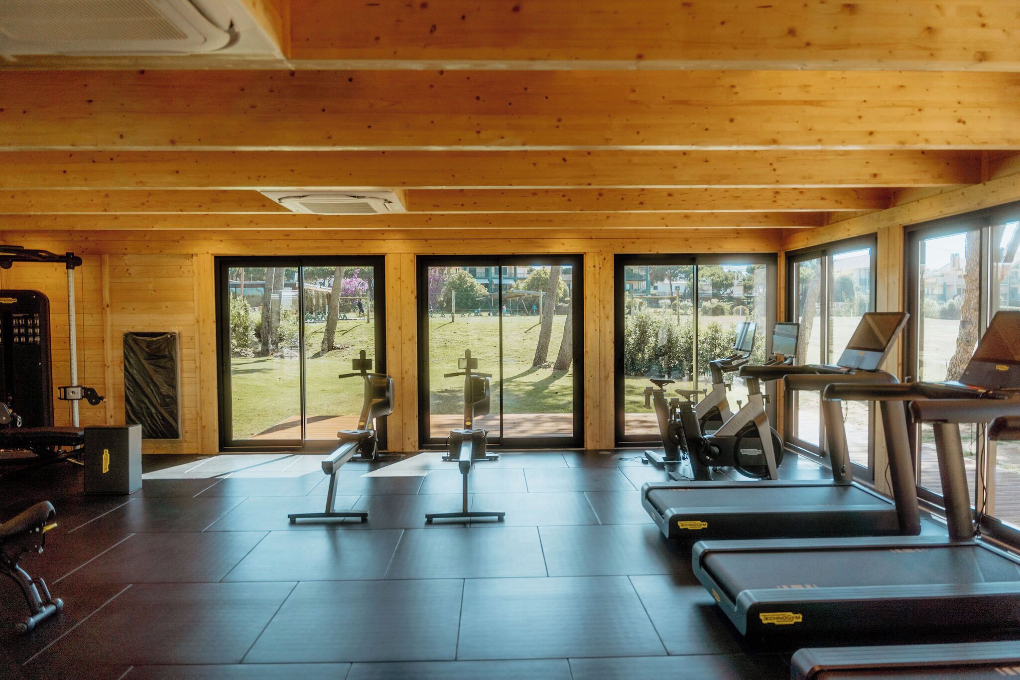 A gym with exercise equipment, large windows, and a view of the outdoors.