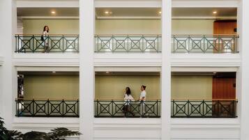 Un hotel de varios pisos con balcones, un atrio central y una puerta de madera a la derecha.