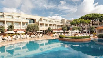 A hotel with a swimming pool, sun loungers, and umbrellas.