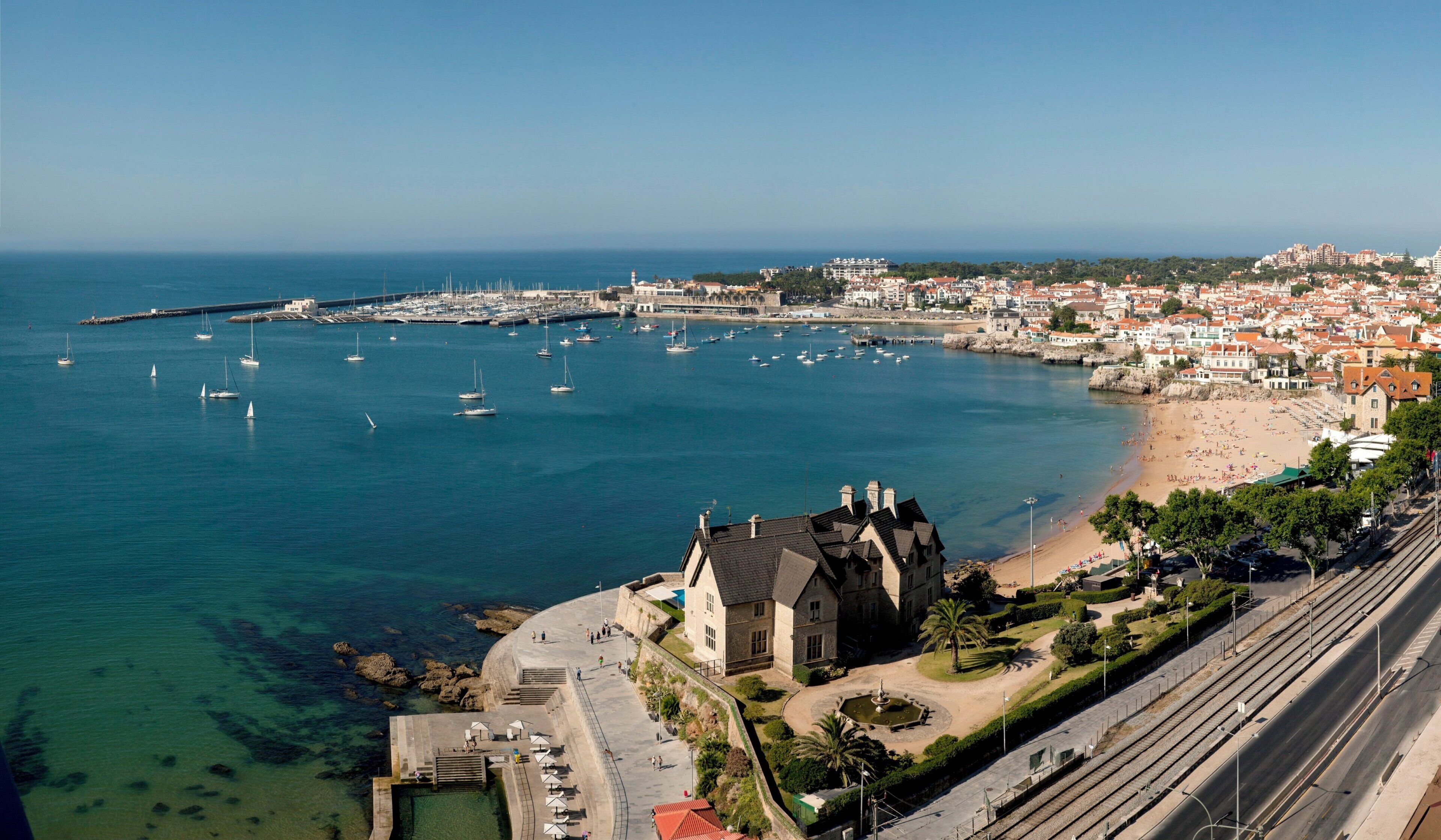 Un pueblo costero con puerto deportivo, playa y edificios históricos.