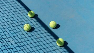 Four tennis balls on a blue surface with a net.