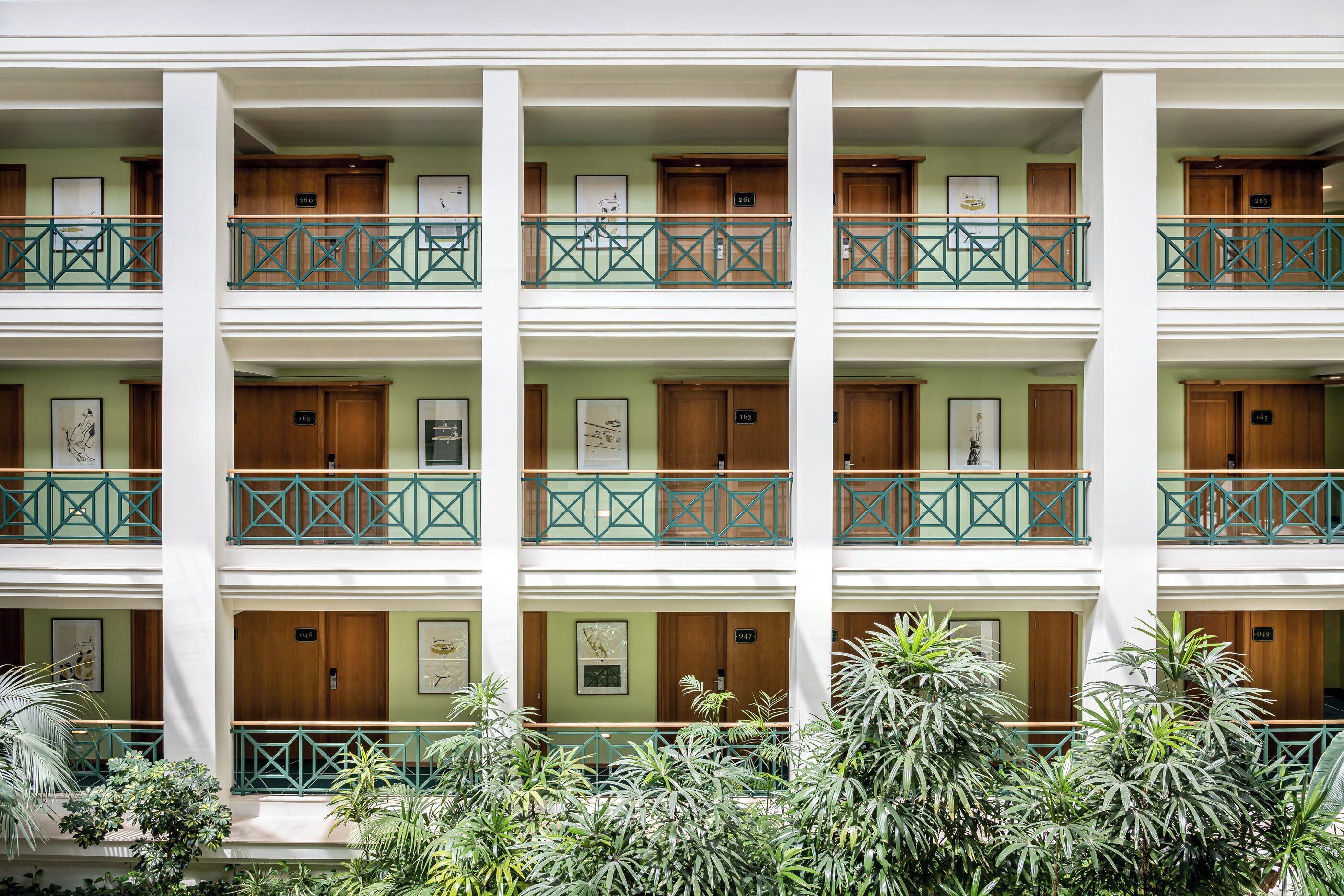 A multi-story hotel with balconies, wooden doors, and framed artwork.