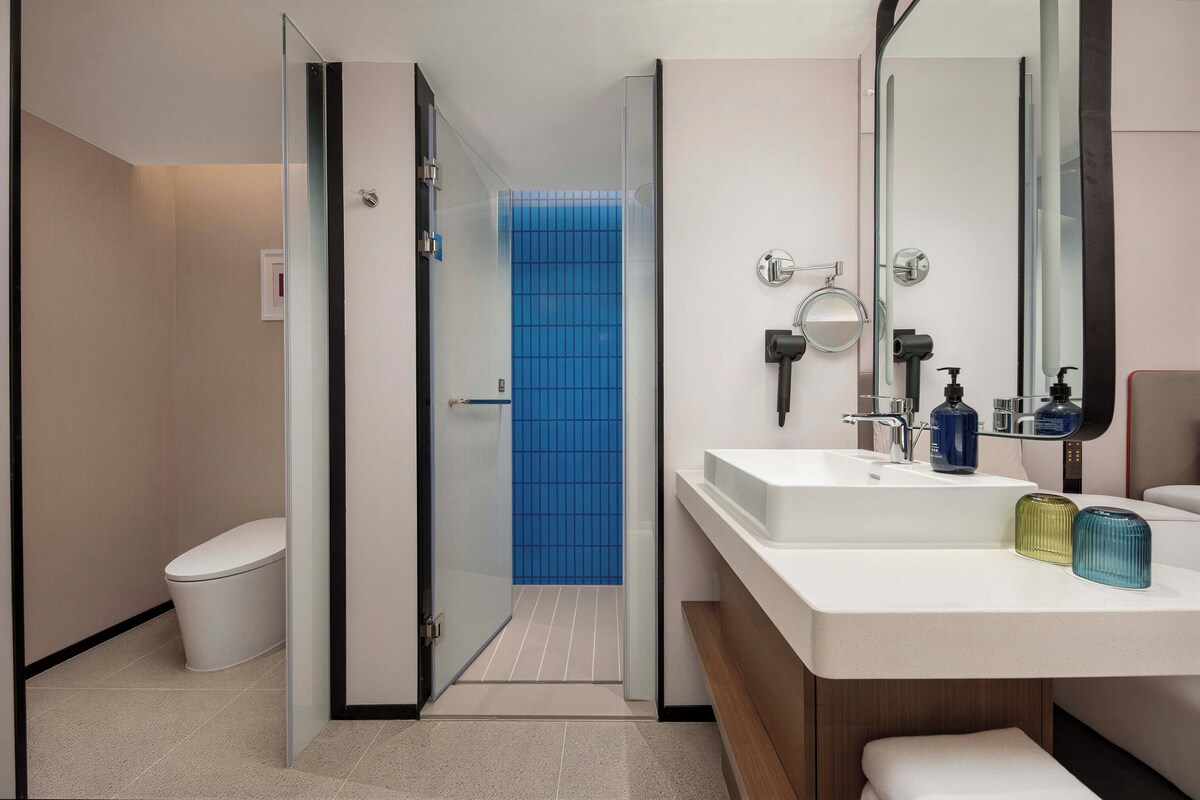 A modern bathroom with a white sink, mirror, and two bottles of soap.