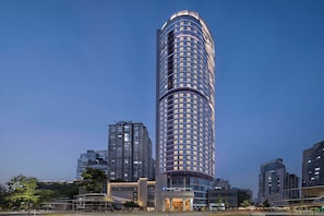 A tall, modern hotel with a curved facade and a prominent entrance.