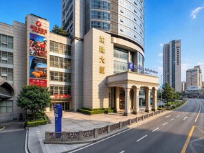 A modern hotel with a prominent entrance, large windows, and a clear sky. - Holiday Inn Express Chongqing Yangjiaping by IHG (Chongqing)