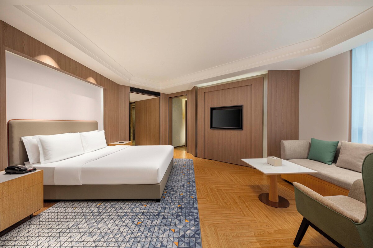 A hotel room with a bed, a sofa, a TV, and a small table.