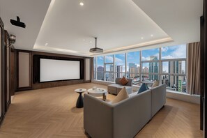 A modern living room with a large screen, comfortable seating, and a city view. - Holiday Inn Express Chongqing Yangjiaping by IHG (Chongqing)