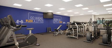 Une salle de sport équipée de divers appareils d’exercice, un mur bleu orné d’un texte motivant et un plafond doté d’un éclairage encastré.