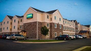 A multi-story hotel with a stone facade, a sign indicating it is a Fairfield Inn & Suites, and a parking lot with several cars.