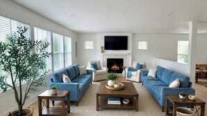 A living room with a fireplace, sofas, a coffee table, and a TV. - Brand New 2026 Villa, 5 min Walk to the Beach, King Canopy Suite, Sleeps 16 (Keansburg)