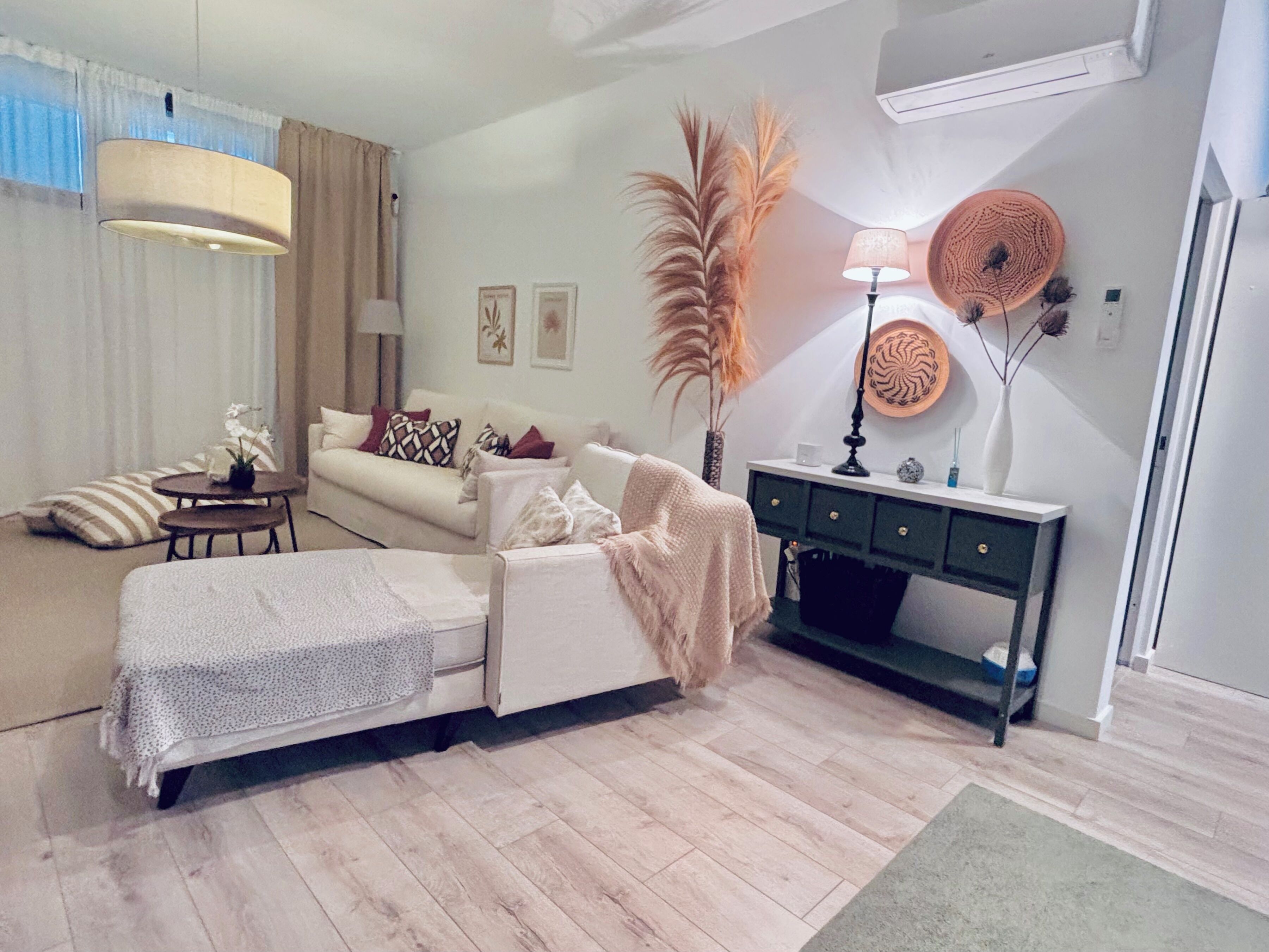 A living room with a sofa, a coffee table, a lamp, a console table, and decorative plants.