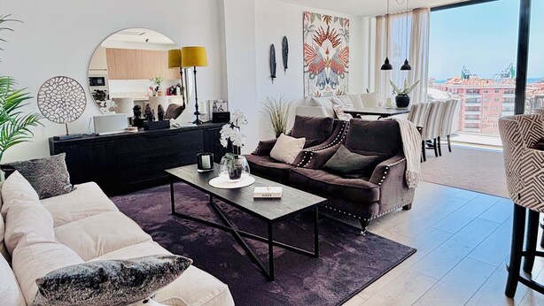Ett modernt vardagsrum med en soffa, ett soffbord och en matplats med stolar.