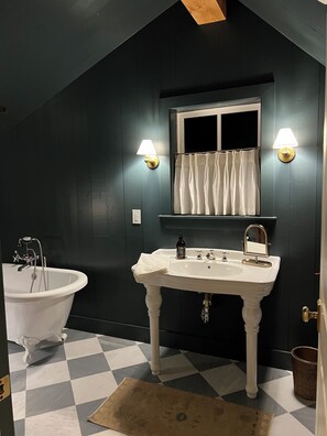 Ein Badezimmer mit einer weißen Badewanne, einem weißen Waschbecken inklusive Spiegel und zwei Wandleuchten.