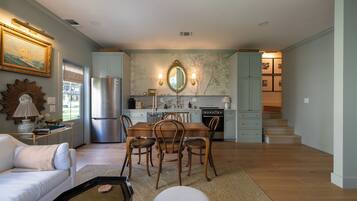 A spacious living area with a dining table, chairs, a sofa, and a kitchen in the background.