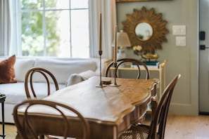 A dining area with a wooden table, metal chairs, a candle holder, and a mirror on the wall. - Brand New Cottage, Prime Location, Fire Pit! (Fredericksburg)