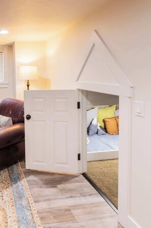 A room with a bed, a door leading to another room, a lamp, and a patterned rug. - Tramway Base camp: Your home away from home close to the best recreation in Utah (Sandy)