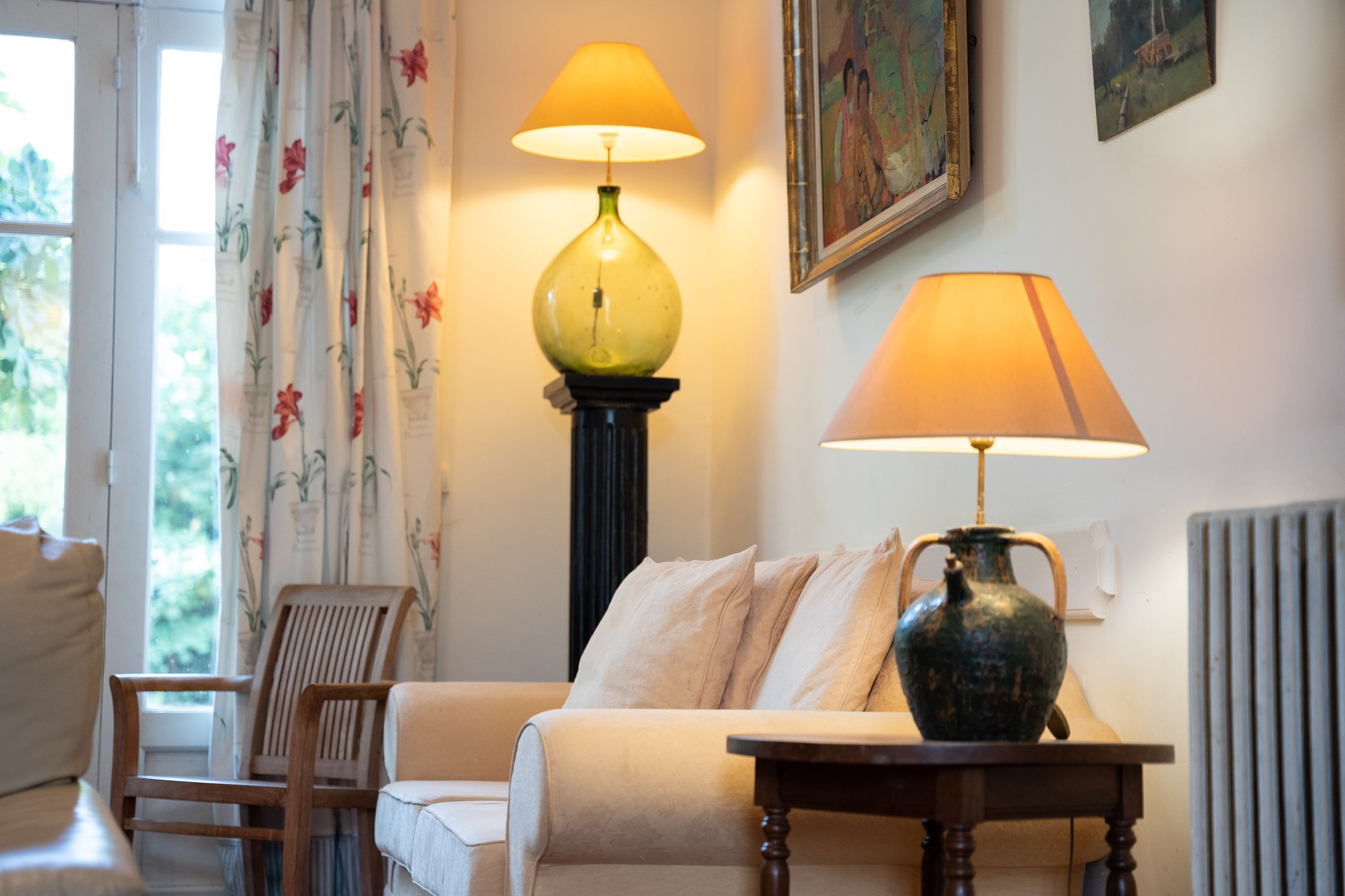 A room with a sofa, two lamps, a vase, and a chair.