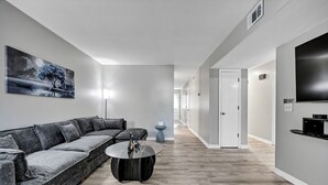 A modern living room with a grey sectional sofa, a round coffee table, and a painting on the wall. - Southern Oasis-Modern Comfort, Minutes from Downtown (Columbia)