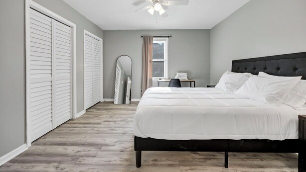 A bedroom with a bed, a ceiling fan, a desk, and a window. - Southern Oasis-Modern Comfort, Minutes from Downtown (Columbia)