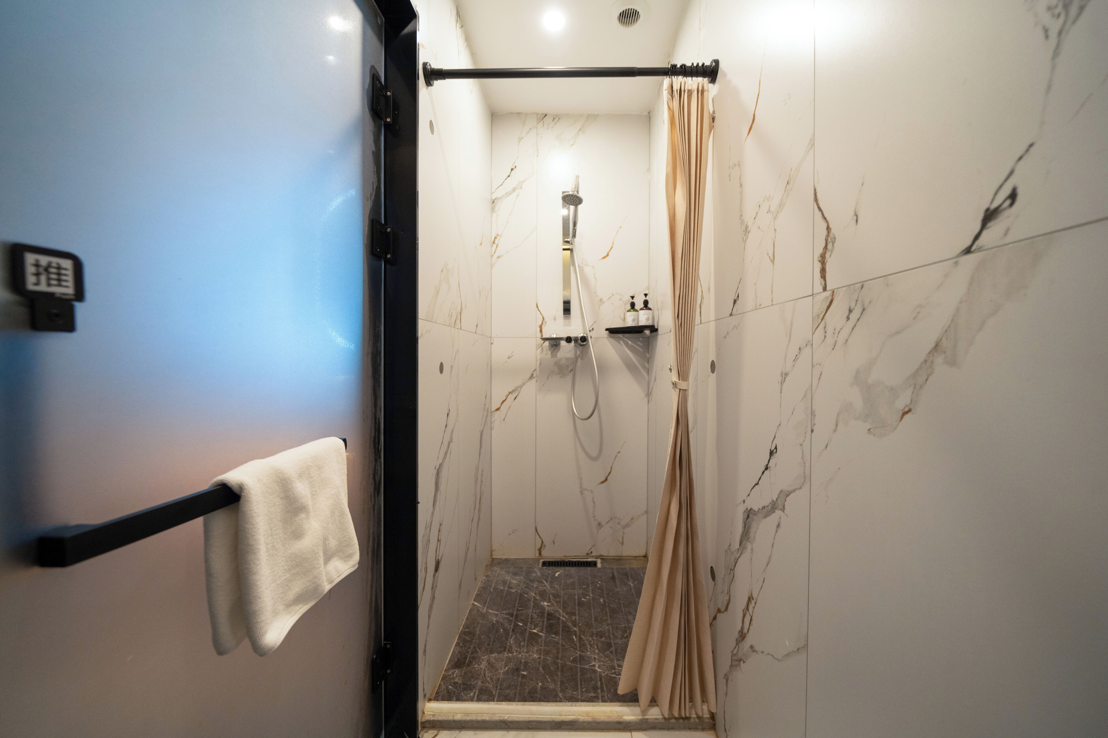 Une salle de bain équipée d’une douche, d’un porte-serviettes et d’un support à papier toilette.