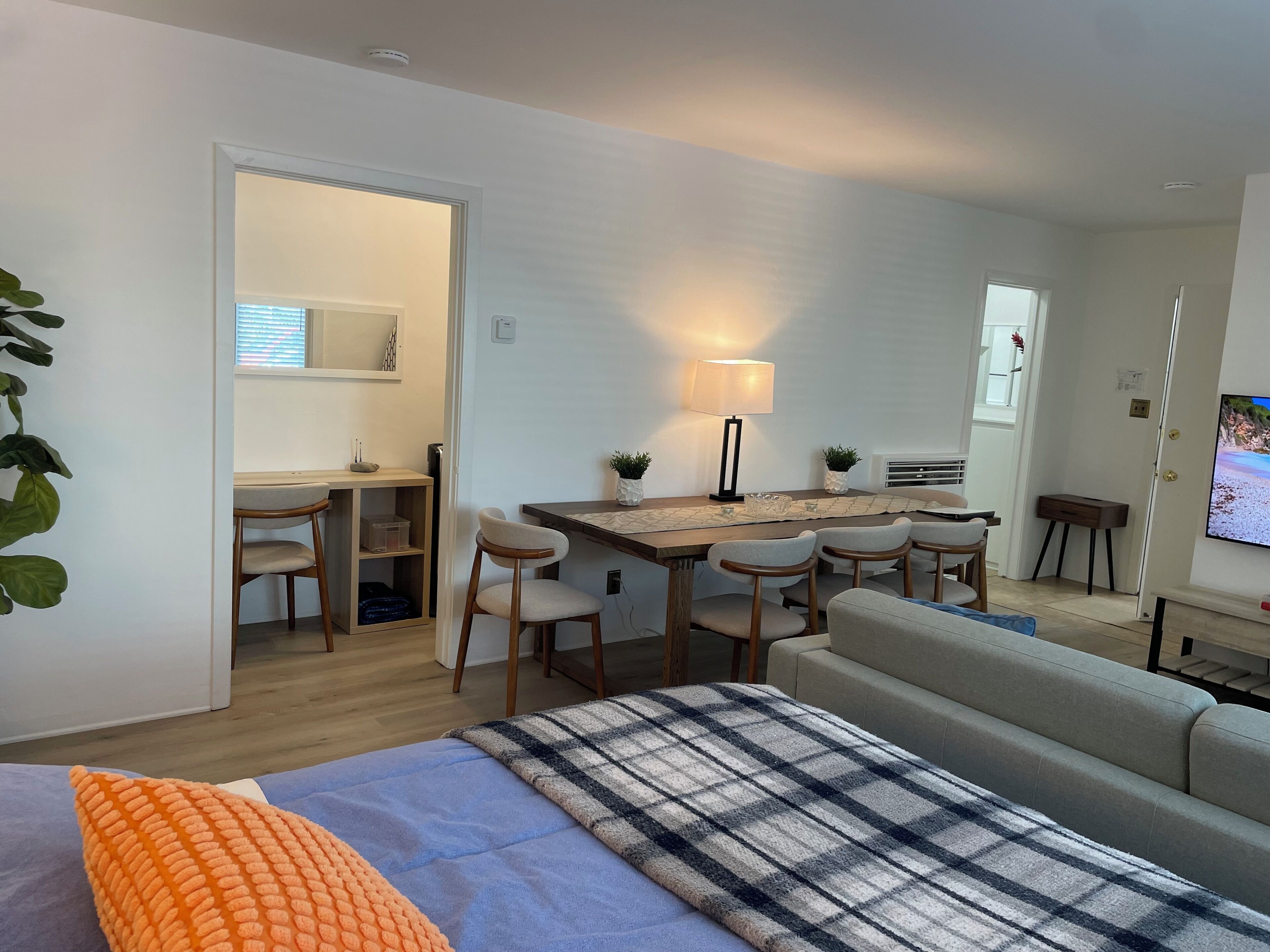 Een moderne woonkamer met een bank, een eettafel met stoelen, een televisie en een klein keukenhoekje.