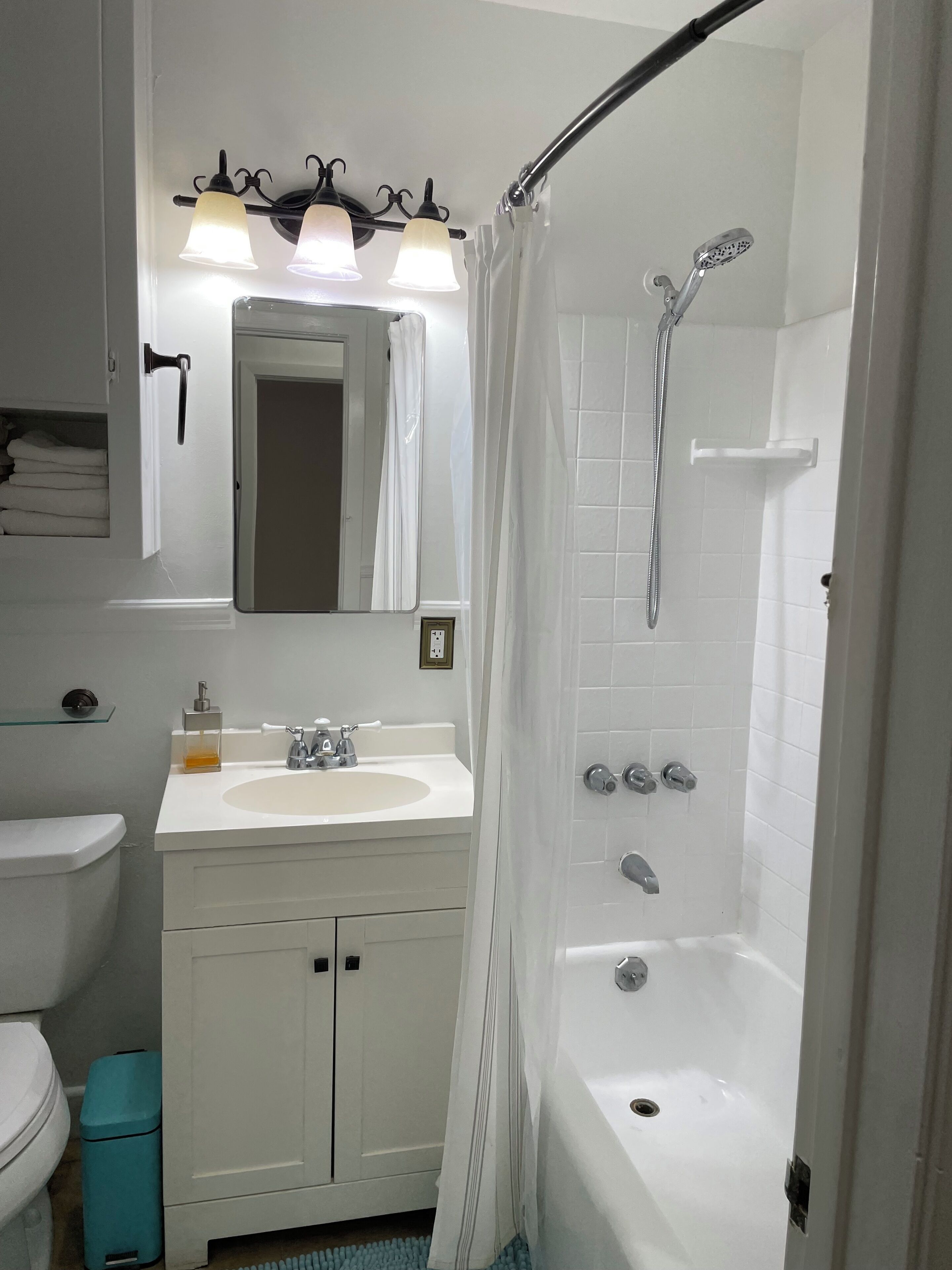 Een badkamer met een witte wastafel, spiegel en douche.